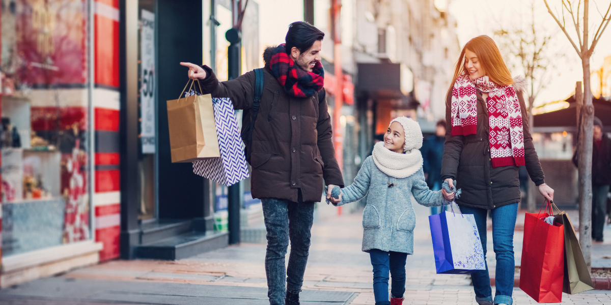 Family walking down the sidewalk with shopping bags