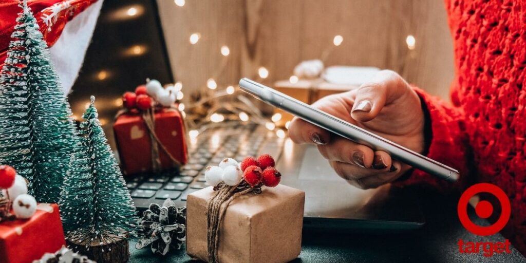 Person on a phone in front of a laptop with Christmas decorations